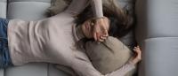 Peaceful pretty 20s girl lying on back on comfortable couch, covering eyes with hand, trying to relax, sleeping at daytime, feeling tired, stressed, fatigued, chronic stress